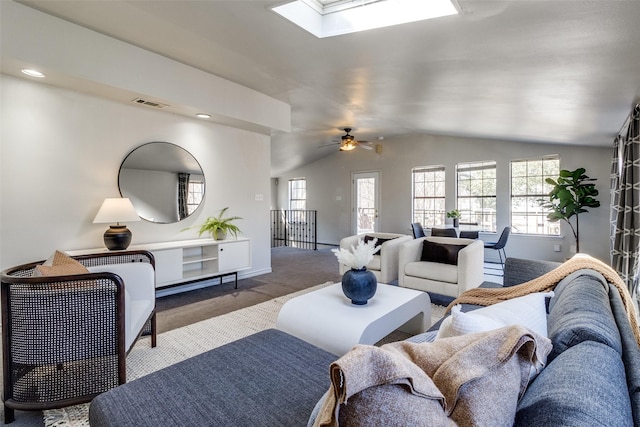 carpeted living room featuring visible vents, baseboards, recessed lighting, vaulted ceiling with skylight, and a ceiling fan