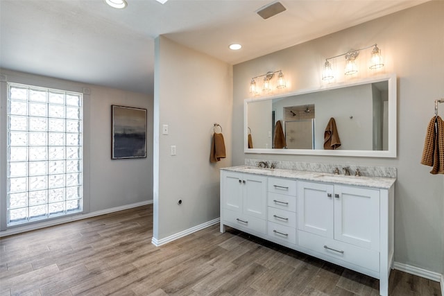 bathroom featuring double vanity, wood finished floors, baseboards, and a sink