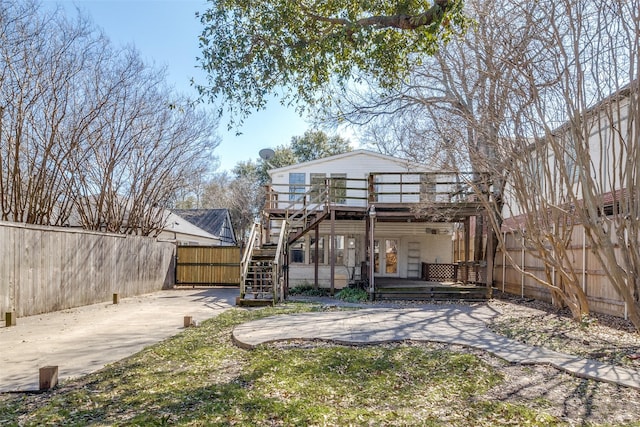 rear view of house with a deck, stairs, and fence