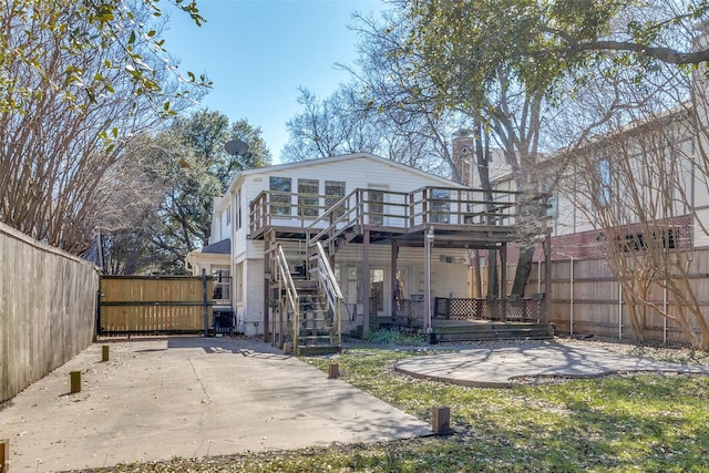 rear view of house featuring a gate, stairway, a wooden deck, fence private yard, and a patio area