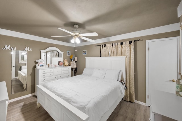 bedroom featuring baseboards, wood finished floors, and a ceiling fan