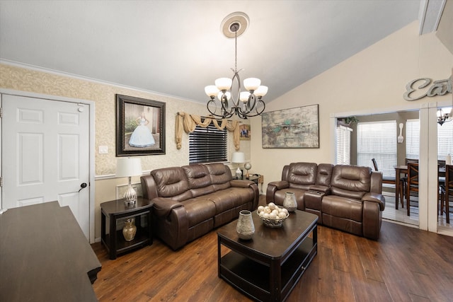 living area with lofted ceiling, crown molding, a notable chandelier, and wood finished floors