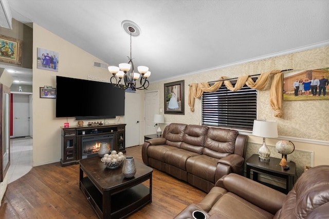 living room featuring wood finished floors, visible vents, an inviting chandelier, lofted ceiling, and a lit fireplace