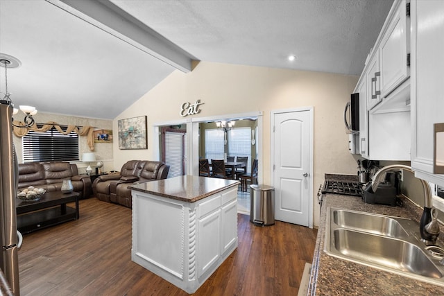 kitchen featuring dark countertops, open floor plan, an inviting chandelier, and a sink