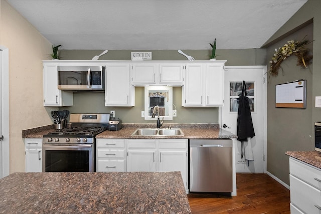 kitchen with baseboards, a sink, stainless steel appliances, dark wood-type flooring, and white cabinets