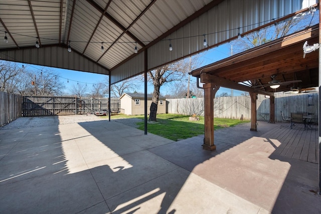 view of patio / terrace featuring an outdoor structure, a storage unit, a fenced backyard, and ceiling fan