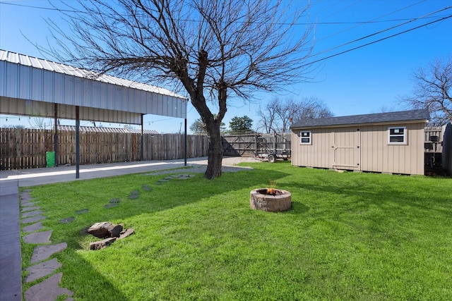 view of yard with a storage shed, an outbuilding, a fire pit, and a fenced backyard