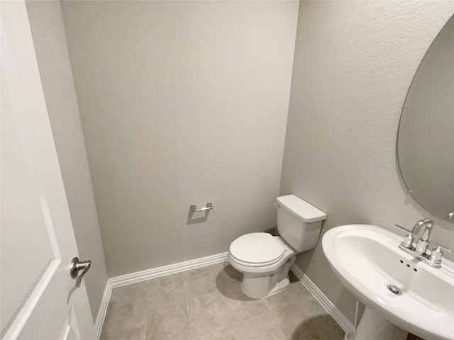 bathroom with tile patterned flooring, toilet, baseboards, and a sink