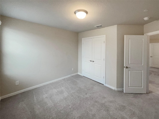 unfurnished bedroom featuring visible vents, carpet floors, baseboards, and a closet