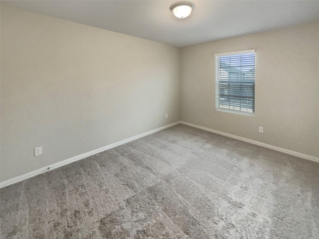 carpeted spare room featuring baseboards