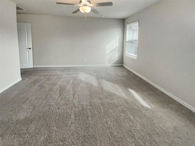 carpeted empty room with a ceiling fan and baseboards