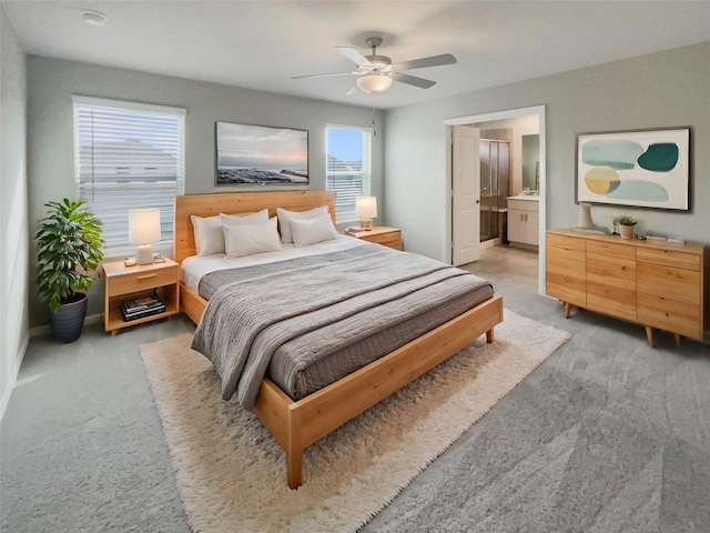 bedroom with light colored carpet, connected bathroom, and a ceiling fan