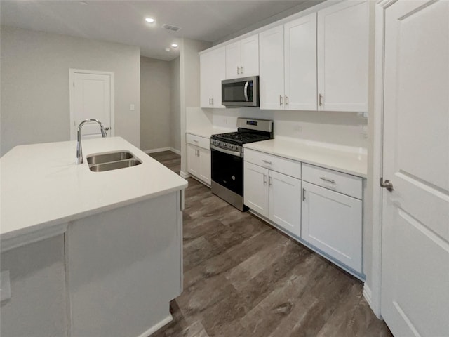 kitchen featuring white cabinetry, stainless steel appliances, dark wood-type flooring, and a sink