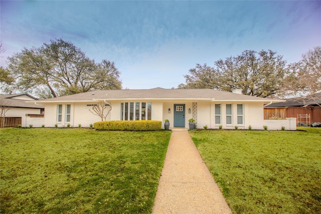 ranch-style home featuring a front lawn, fence, and brick siding