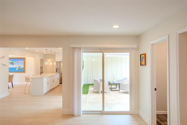 doorway with recessed lighting, light wood-type flooring, and baseboards