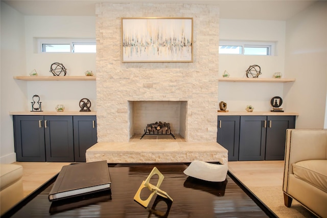 living room featuring plenty of natural light, a stone fireplace, and wood finished floors