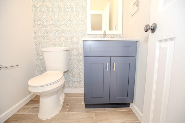 bathroom featuring wood tiled floor, baseboards, toilet, and vanity