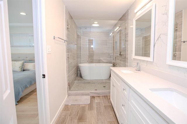 ensuite bathroom featuring wood finished floors, ensuite bath, a soaking tub, double vanity, and a sink