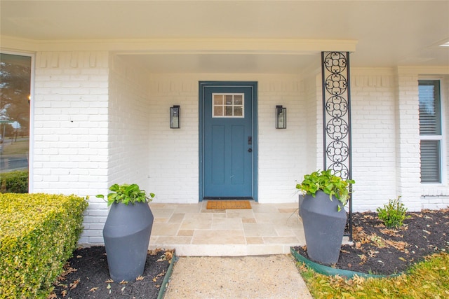 property entrance featuring brick siding and a porch