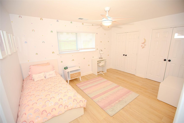 bedroom with light wood-style floors, two closets, visible vents, and a ceiling fan