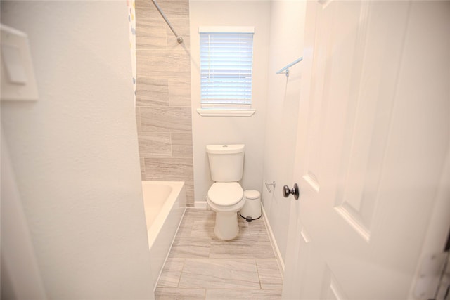 bathroom with toilet, baseboards, and washtub / shower combination