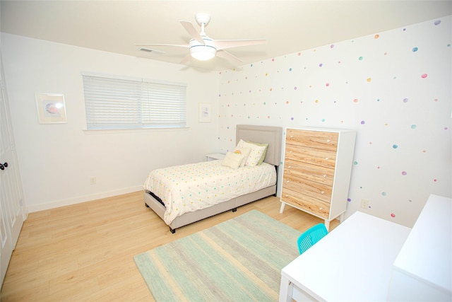 bedroom with light wood-type flooring, visible vents, baseboards, and wallpapered walls