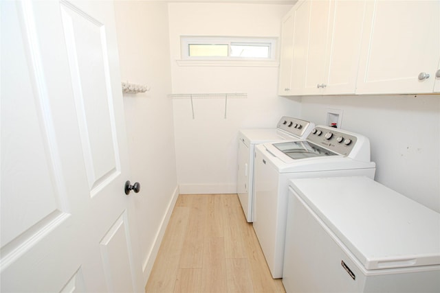 laundry room with washer and clothes dryer, cabinet space, light wood-type flooring, and baseboards