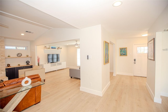 interior space featuring visible vents, baseboards, open floor plan, vaulted ceiling, and light wood-style floors