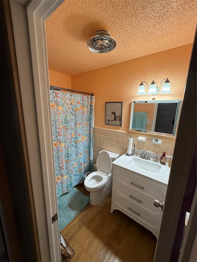 bathroom featuring a wainscoted wall, a textured ceiling, wood finished floors, tile walls, and vanity