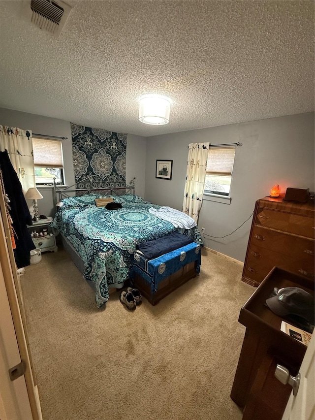 bedroom with multiple windows, carpet flooring, and a textured ceiling