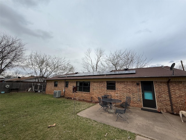 rear view of property with a patio area, a lawn, cooling unit, and brick siding