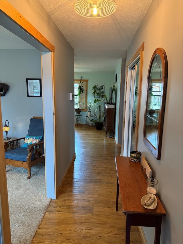 hallway with a textured ceiling and wood finished floors