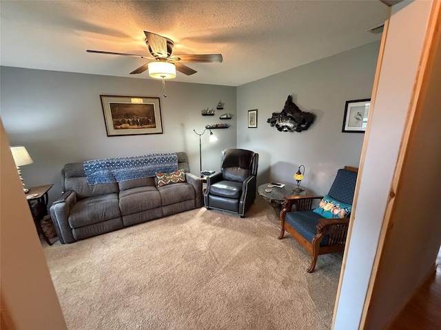 living area featuring carpet flooring, visible vents, a textured ceiling, and a ceiling fan