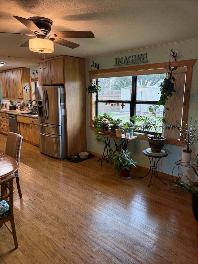 kitchen with brown cabinetry, light wood-style flooring, appliances with stainless steel finishes, and a sink