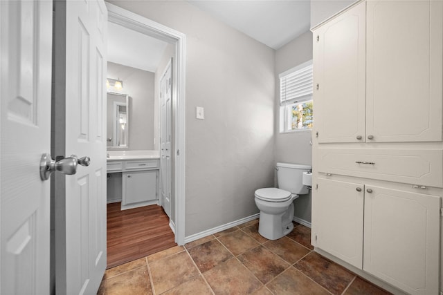 half bath featuring vanity, toilet, and baseboards