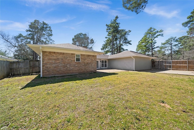 rear view of house with a patio area, brick siding, a fenced backyard, and a lawn