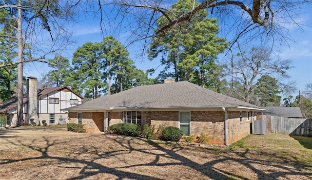 exterior space with brick siding, fence, a front yard, roof with shingles, and a chimney