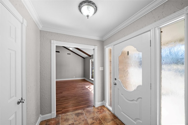 foyer with ornamental molding, stone finish flooring, a textured wall, baseboards, and vaulted ceiling