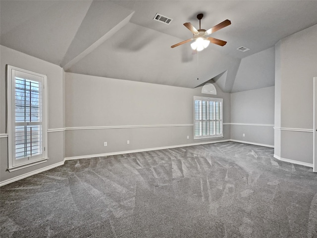 carpeted spare room featuring vaulted ceiling, plenty of natural light, and visible vents