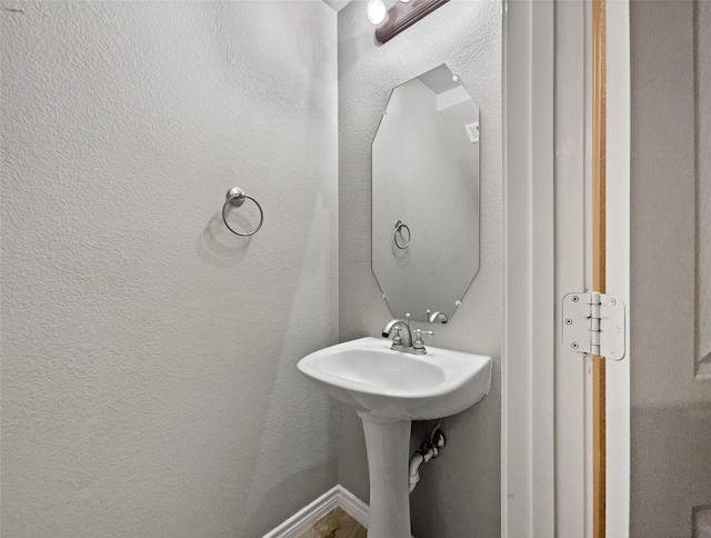 bathroom with baseboards and a textured wall