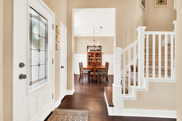 foyer entrance with stairway, baseboards, dark wood-type flooring, and an inviting chandelier