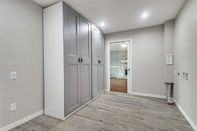 laundry area with cabinet space, a fireplace, light wood finished floors, baseboards, and hookup for an electric dryer