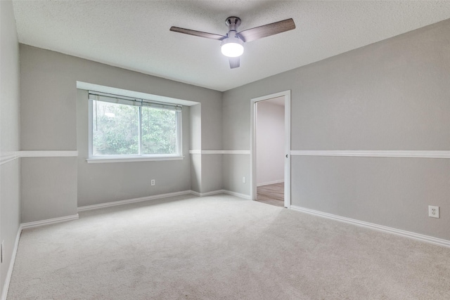 carpeted empty room featuring baseboards, a textured ceiling, and a ceiling fan