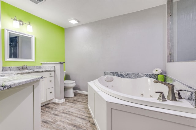 full bathroom featuring visible vents, a jetted tub, toilet, wood finished floors, and vanity