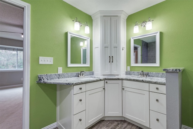 full bathroom featuring double vanity, baseboards, and a sink