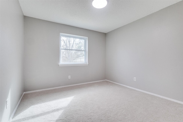 carpeted spare room with a textured ceiling and baseboards