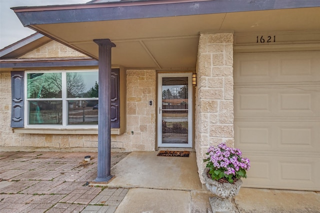 entrance to property featuring a garage and stone siding