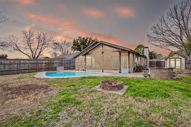 back of house featuring an outbuilding, a fenced in pool, a fire pit, and a fenced backyard