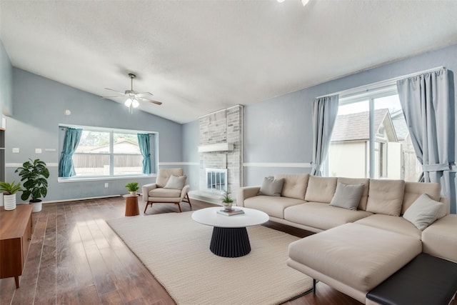 living room featuring a fireplace, lofted ceiling, wood finished floors, and a wealth of natural light