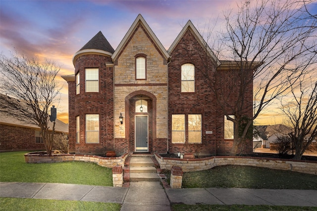 view of front of house featuring a yard, brick siding, and stone siding